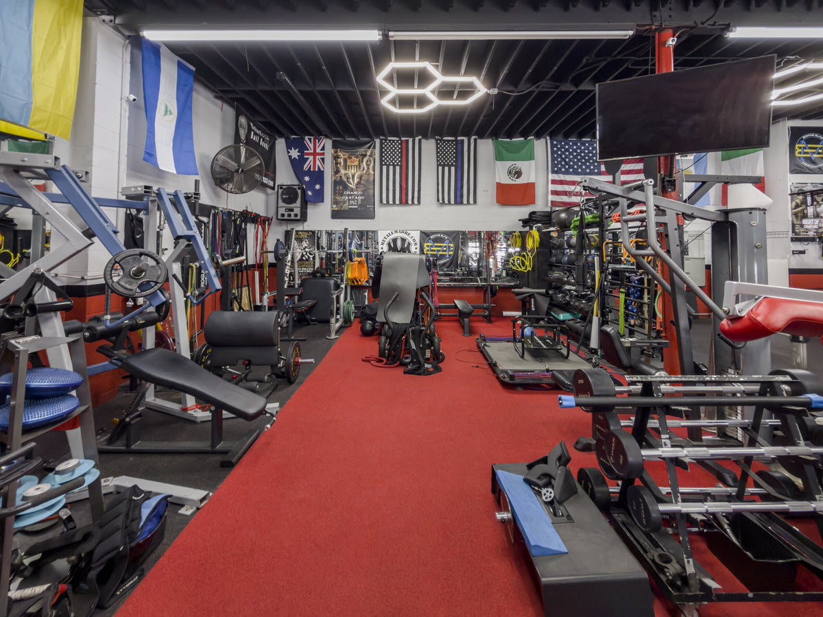Red training aisle between strength machines beneath international flags