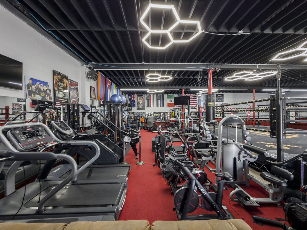 Cardio machines beside the red training aisle at Knockouts Boxing Facility